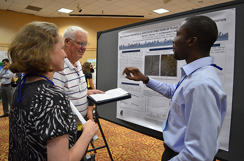 Two Scientists and a Farmer Discuss a Tillage Poster